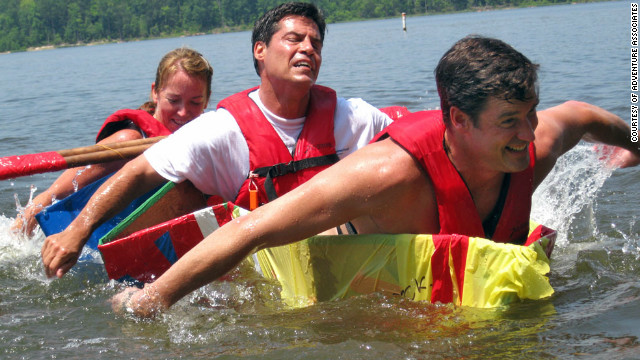 Executive participants strain to stay afloat as they attempt to cross a lake in a vessel they have built on an Adventure Associates retreat in North Carolina, USA.