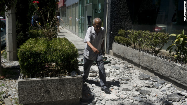 A man walks over debris from a building in Mexico City.