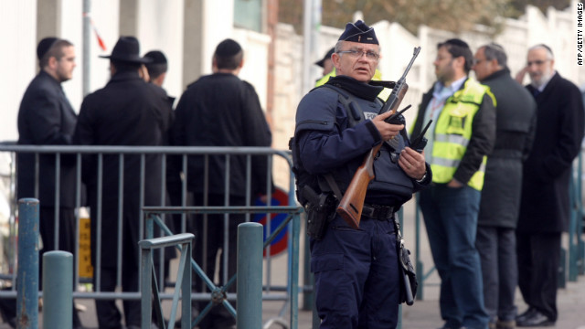 A policeman stands guard on Tuesday in front of the Jewish school where four people were killed the day before in Toulouse.
