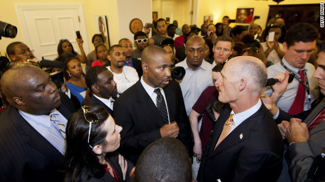 Tallahassee defense attorney Deveron Brown talks to Florida Gov. Rick Scott, right, about the shooting of Trayvon Martin.