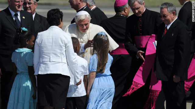 Pope Benedict XVI is welcomed by children as Cuban President Raul Castro looks on upon arrival to Santiago de Cuba on Monday, March 26. Fourteen years after Pope John Paul II visited Cuba, Pope Benedict is making his first trip to the communist country.