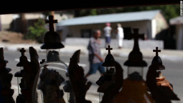 People walk by religious items for sale at Basilica del Cobre, the shrine to Our Lady of Charity of El Cobre, Cuba's patron saint on March 25.