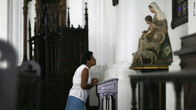 A woman prays before the start of services at Santo Angel Custodio church.