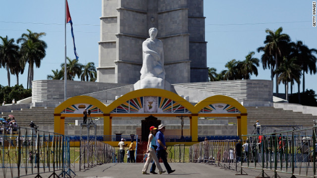On Saturday, people walk past the stage set up for Pople Benedict XVI in Havana.