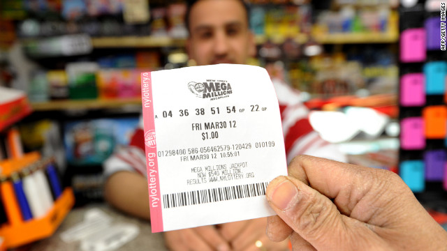 A man shows his Mega Millions ticket in front of clerk Abdulwali Mohamed Osaim at a convenience store on Manhattan's East Side.