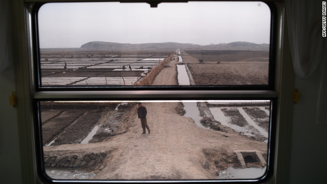 Workers and farms are seen through the window of a train as it passes through the country Sunday.
