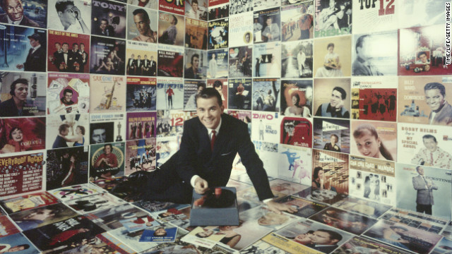 Clark sits in a room decorated floor to ceiling with record album covers circa 1958.