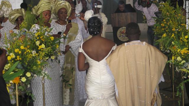 A Nigerian couple make their way up the aisle, with the bride wearing a white gown and the groom in traditional attire.