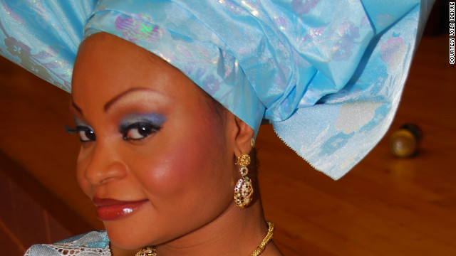 A bride wears a bright-hued outfit with embroidered detailing and traditional Nigerian gele headdress. 