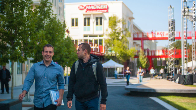 Facebook team members walk across the company's sprawling new campus on their way to Thursday night's Hackathon kickoff event. 