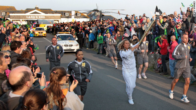 Surfer Tassy Swallow carries the flame as it leaves Land's End. She is one of 8,000 torch-bearers who will transport the flame on its 70-day journey to the Olympic Stadium in east London.