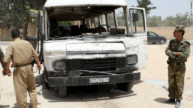 Syrian military officers inspect a damaged bus following a deadly explosion Wednesday.