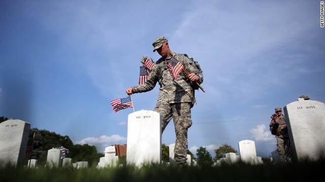 Members of the 3rd U.S. Infantry Regiment place flags at the graves of U.S. soldiers buried at Arlington National Cemetery.