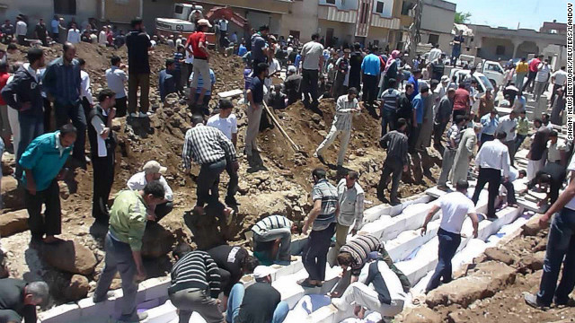 People gather at a mass burial for victims in Houla in this handout image dated May 26.