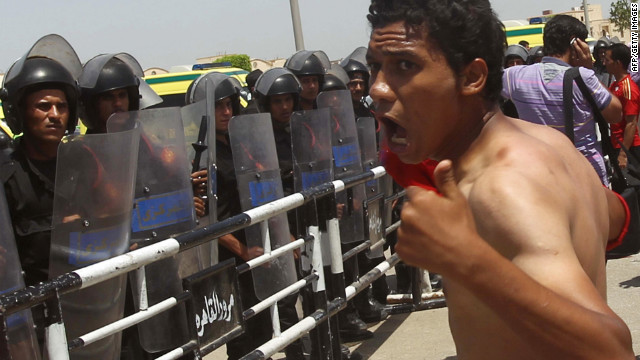 An anti-Mubarak protester shouts before a line of riot policemen guarding the Cairo courthouse.