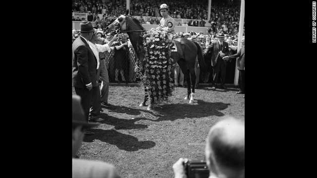 Count Fleet, who won the Triple Crown in 1943, is adorned with a garland of flowers after winning the Preakness Stakes in 1943. 