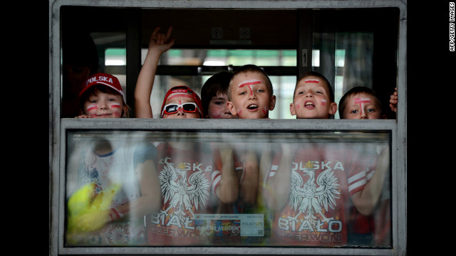 Fans of Poland's national soccer team wave from a train window.