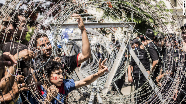 Protestors gesture towards military police through a barricade of barbed wire during a protest against presidential candidate Ahmed Shafiq outside the Supreme Constitutional Court on Thursday.