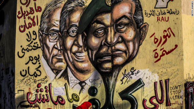 People walk past graffiti showing faces of ousted Egyptian president Hosni Mubarak, right; Field Marshal Hussein Tantawi, second right; former Secretary General of the Arab League Amr Mussa, second left, and former prime minister and presidential candidate Ahmed Shafiq, left, at Tahrir square. 