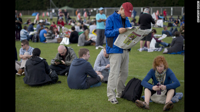 Tennis fans pass the time as they wait in line for tickets outside the stadium June 26.