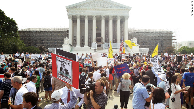 Journalists and supporters and protesters of the health care law gather outside the Supreme Court after the justices ruled in favor of its constitutionality in a narrow decision.