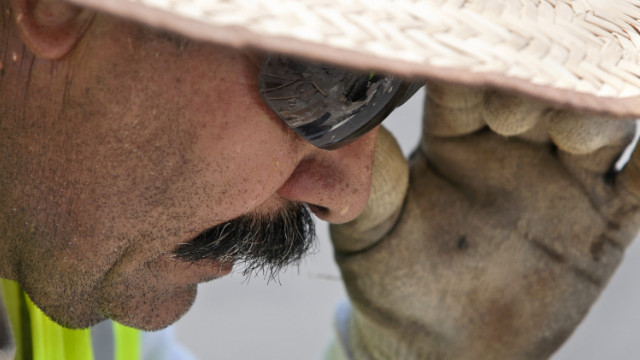 Beads of sweat roll down Francisco Hernandez's face as he works to repave Hillsborough Street in Raleigh, North Carolina, on Friday, June 29.