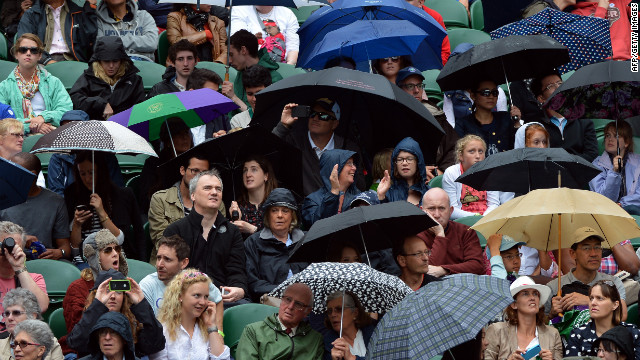 Fans at center court take shelter from the rain under umbrellas during Day Eight of the tournament on Tuesday.