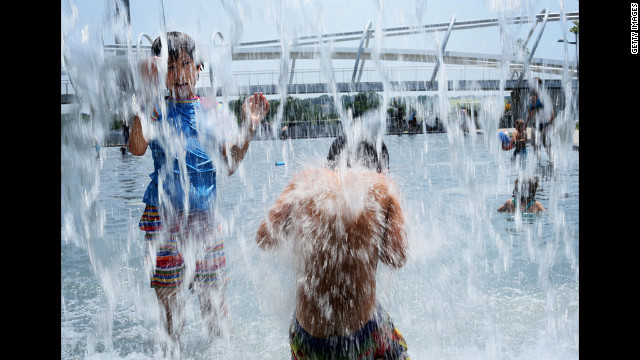 Ten-year-old Lilly Hwang-Geddes, left, of Ithaca, New York, plays in a fountain at the Yards Park on Thursday, July 5, in Washington. A record heat wave has been in the area for more than a week.