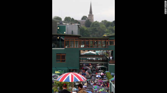 A crowd tries to shelter itself from the rain Friday on day 11 of the Wimbledon Lawn Tennis Championships.