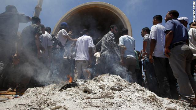 Libyan protesters gather around burned ballot boxes and election materials outside a polling station in Benghazi. They are demanding greater representation during the voting process.