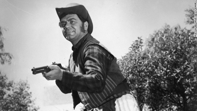 Ernest Borgnine steadies his rifle while acting in a Western film circa 1955.