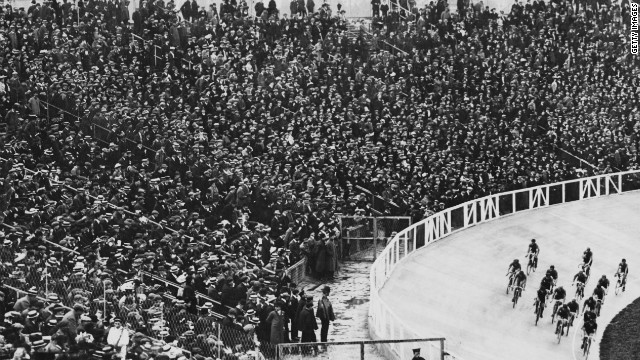 A packed stadium cheers on cyclists during a race. More than 100 years later, the 2012 London Olympics boasts a specially-built Velodrome for cycling, with seating for 6,000 competitors.