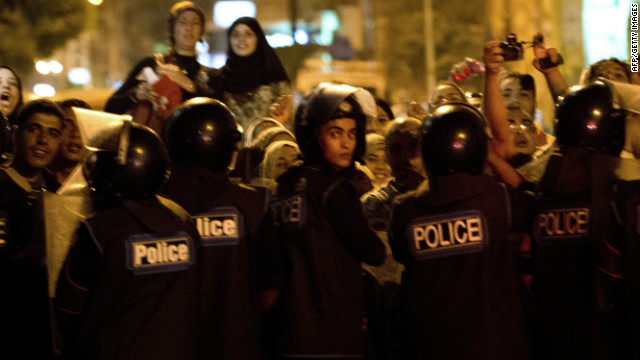 Egyptian riot police stand guard as protesters gather Alexandria on Sunday during visit by Hillary Clinton.