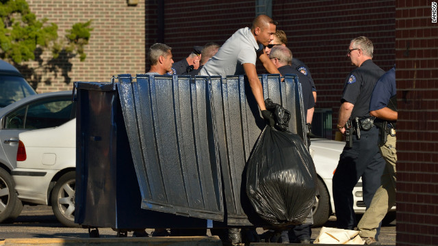 Agents search the trash container outside the suspect's apartment in Aurora.