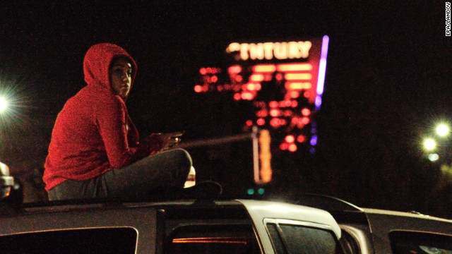 A woman sits on top of her car near the crime scene. 