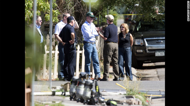 Law enforcement officers speak with Colorado Gov. John Hickenlooper, center, outside the suspect's apartment Saturday. 