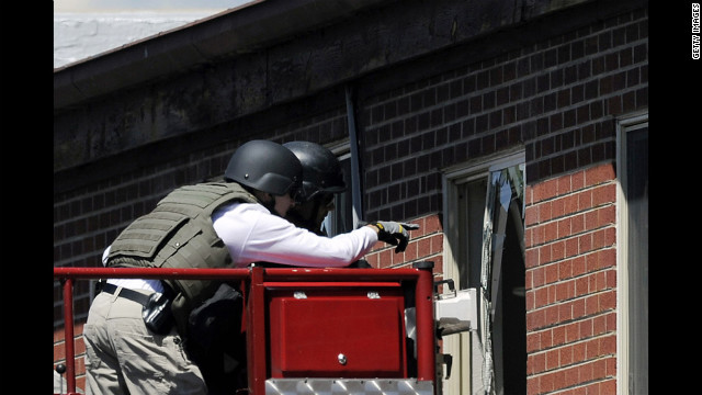 Law enforcement officers prepare to disarm the booby-trapped apartment Saturday.