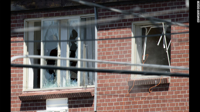 Debris flies out a window, right, after law enforcement officers detonate an explosive device inside the apartment Saturday.