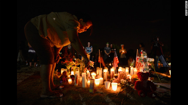 A woman lights a candle at a makeshift memorial where the victims of the massacre are mourned. 