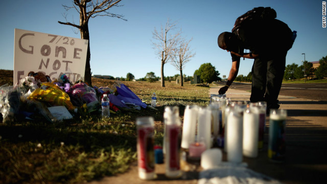 Gerald Wright, 24, relights candles that have blown out at the victims' memorial across from the movie theater.