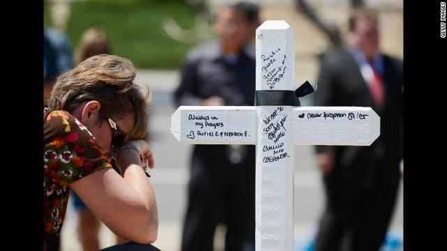 Angie Terry of Alabama prays next to a white wooden cross erected for victims.