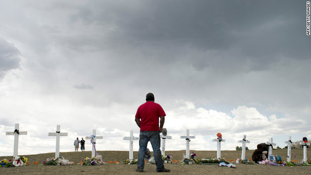 A man pauses before the crosses at the memorial near the Century 16 movie theater on Sunday.