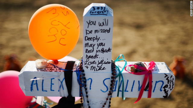 A cross stands at the makeshift memorial for victims across the street from the Century 16 theater on Tuesday.