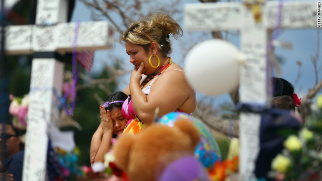 Angella Aquilis, left, and Maria Olivas mourn together at a makeshift memorial across the street from the Century 16 movie theater Wedesday, July 25.