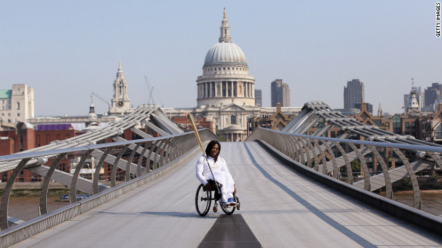 Wheelchair basketball player Adedoyin Adepitan of Great Britain carries the Olympic flame Thursday over Millennium Bridge in front of St. Paul's Cathedral in London.