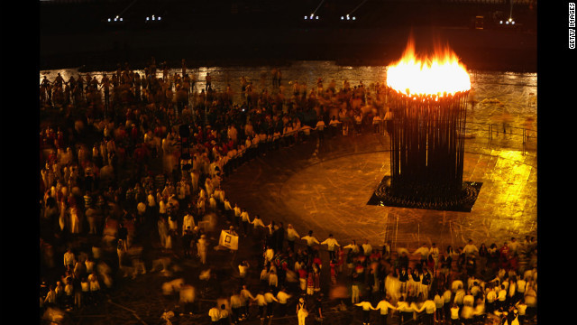 Participants look on as the Olympic flame burns in the cauldron.