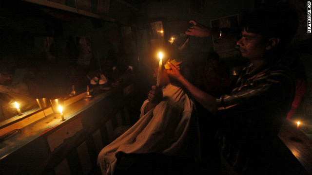 A customer holds a candle as he gets his hair cut at a barber shop in Kolkata on Tuesday.