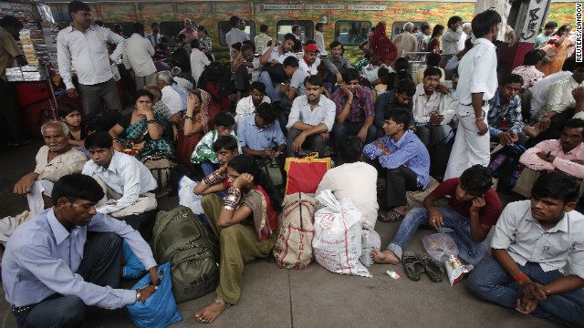 Passengers sit on the platform at train station in New Delhi on Tuesday.