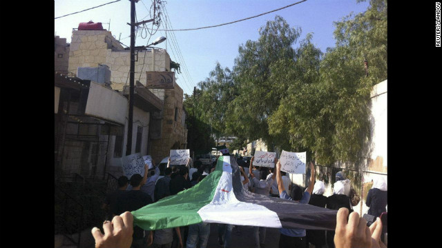 Demonstrators hold an opposition flag during a protest Wednesday against Syria's President Bashar al-Assad in Damascus.
