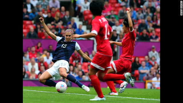 Alex Morgan of the United States strikes the ball while Kim Myong Gum and Pong Son Hwa of North Korea attempt to deflect during the women's soccer first-round match.